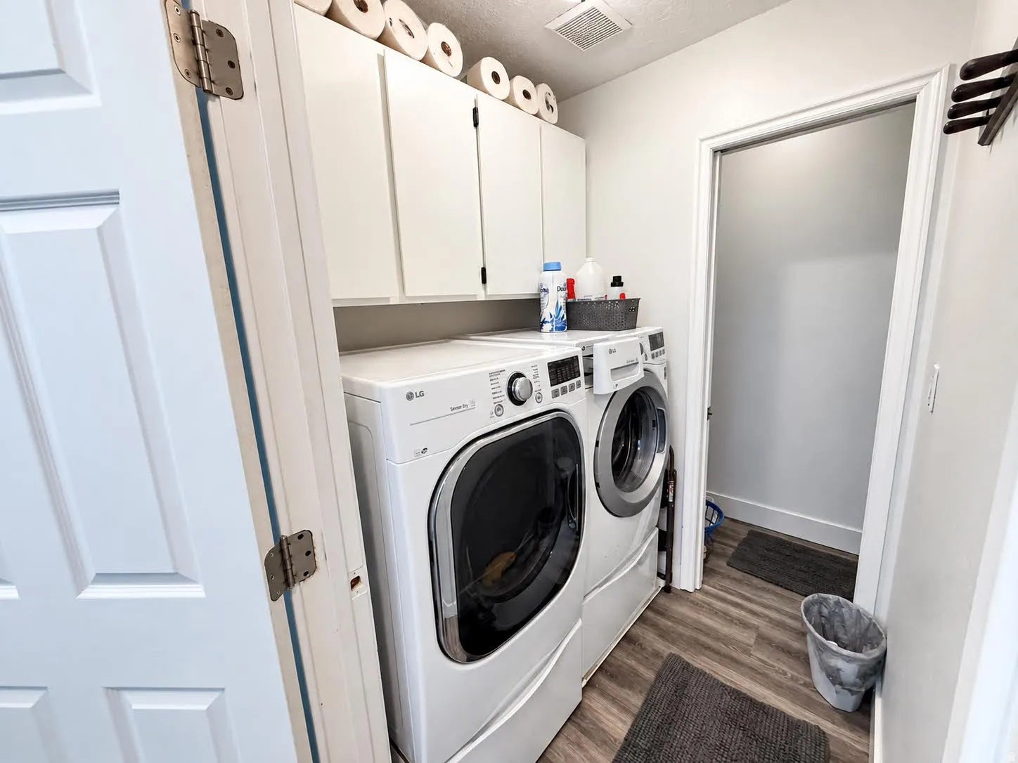 Laundry area featuring overhead cabinetry, wood-finish flooring, and white walls