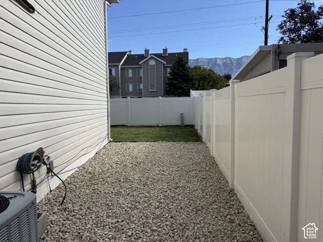 Side yard featuring white vinyl siding, gravel hardscaping, and a white privacy fence