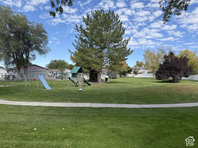 Expansive green space featuring mature trees and a playground structure