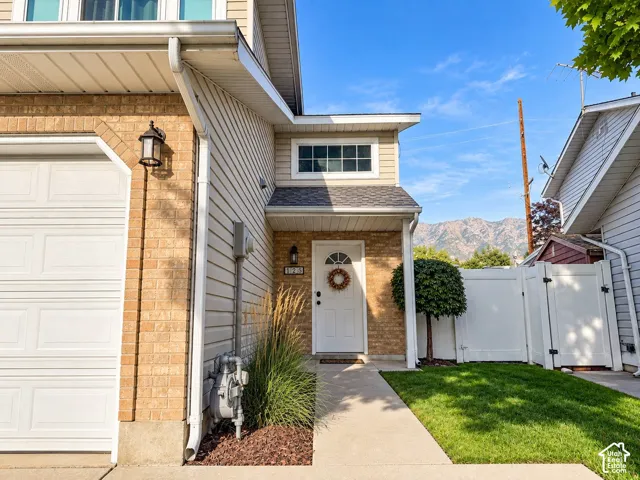 Brick and siding exterior with an attached garage, landscaped entry, and a mountain backdrop