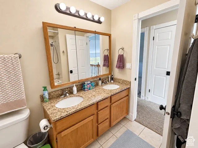 Dual white oval sinks, light wood-finish cabinetry, granite-finish countertop, and tile flooring