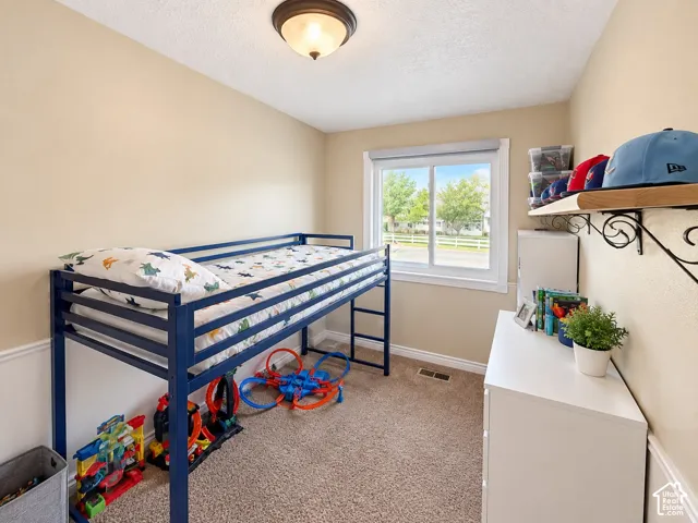 Neutral wall color, carpet flooring, window with white trim, wall-mounted light fixture, decorative wall shelving