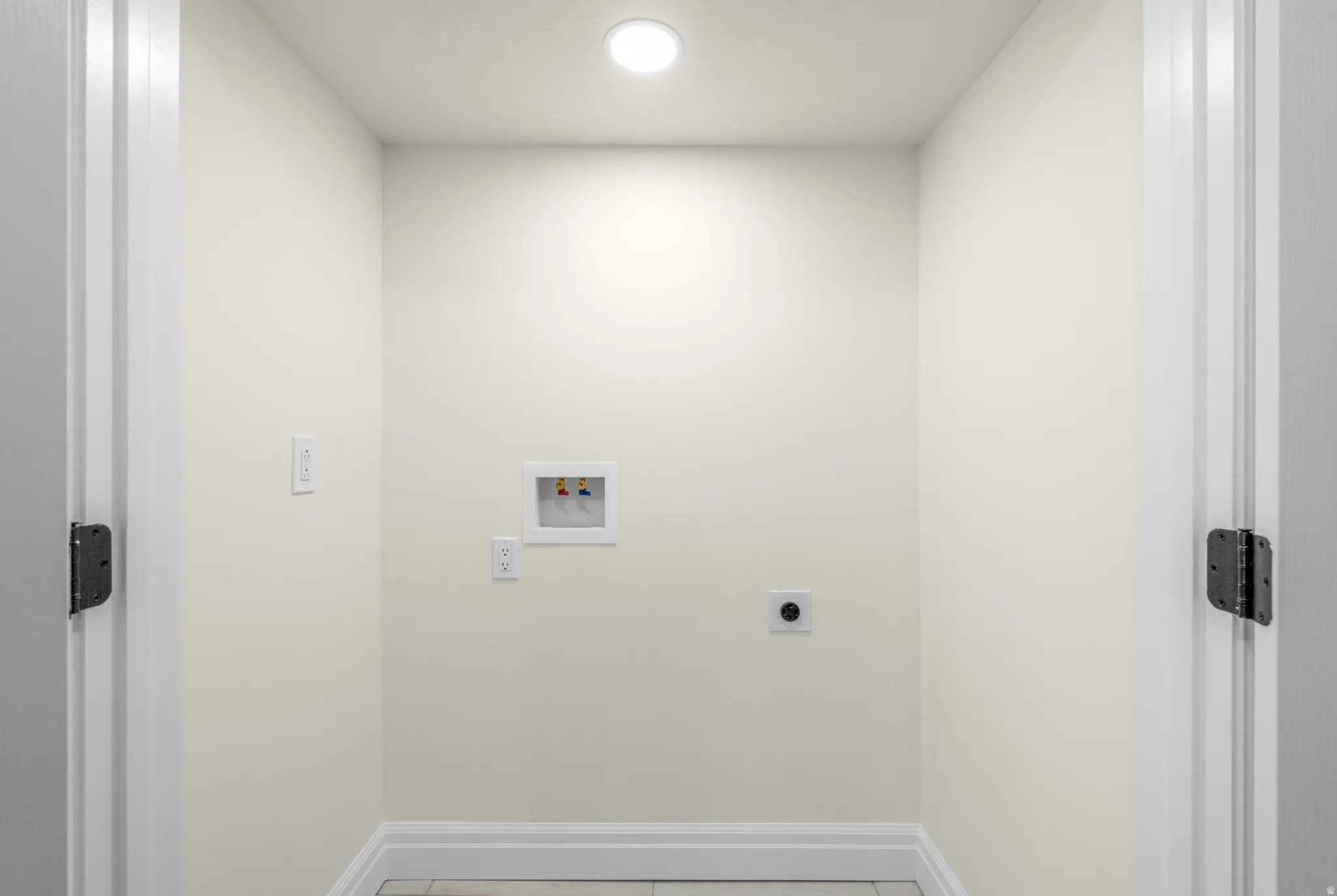Dedicated utility space with flush-mount lighting, appliance hookups, and neutral wall tones