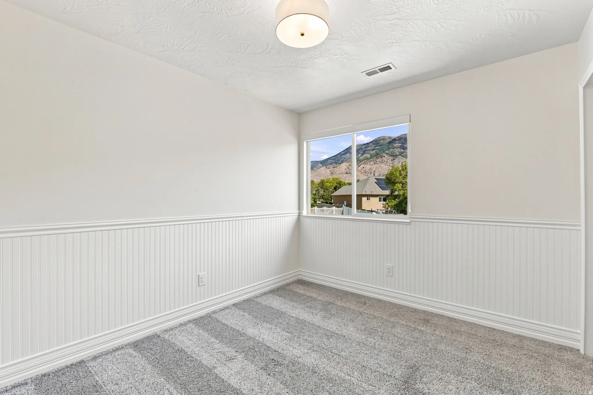 White beadboard wainscoting, neutral walls, and a contemporary ceiling light fixture