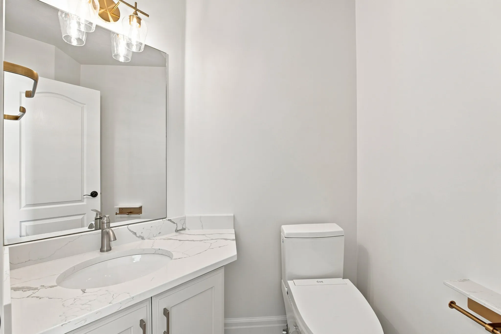 Vanity with a quartz countertop, an undermount sink, a brushed nickel faucet, and a wall-mounted mirror
