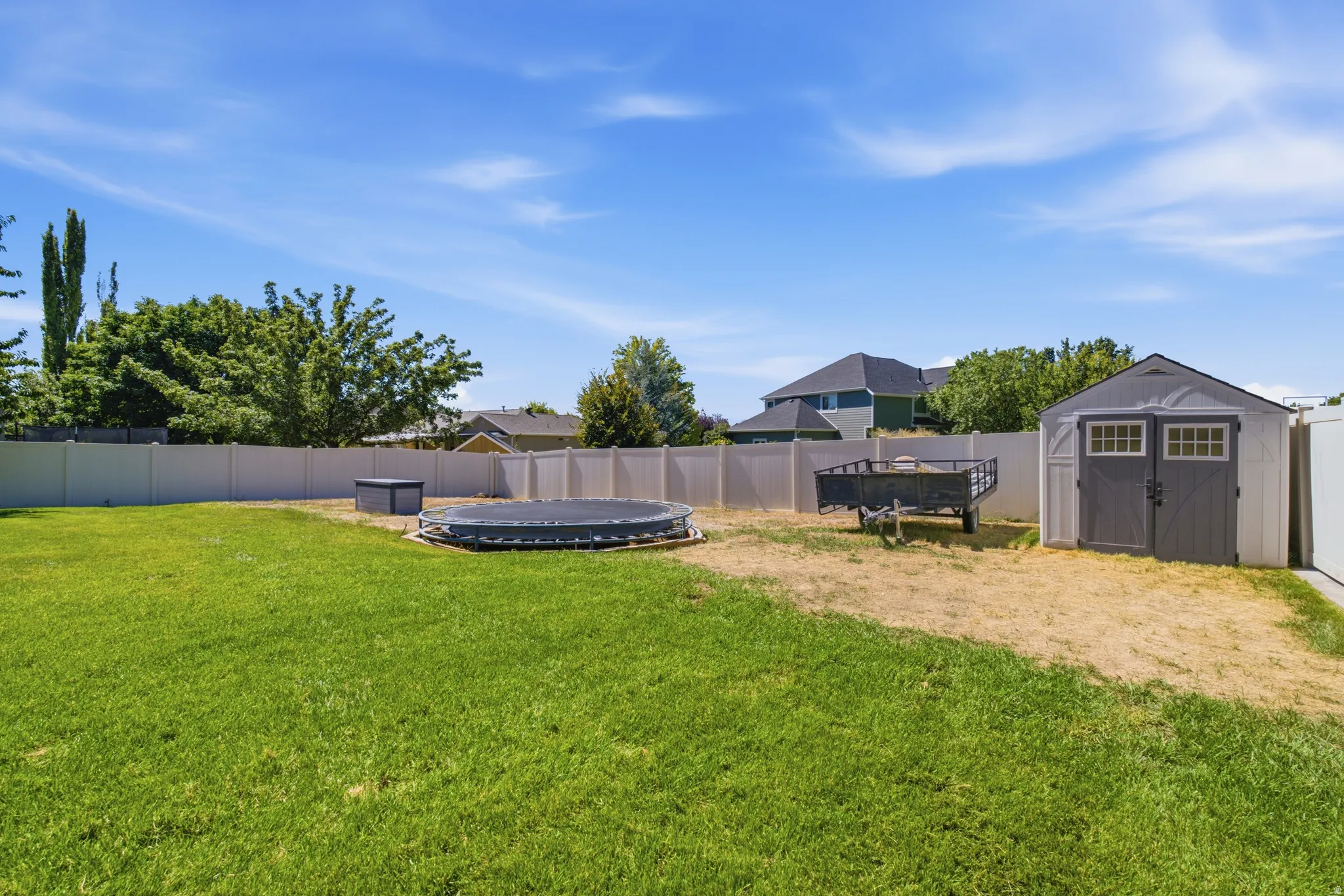 Expansive grassy yard with a privacy fence and a storage shed