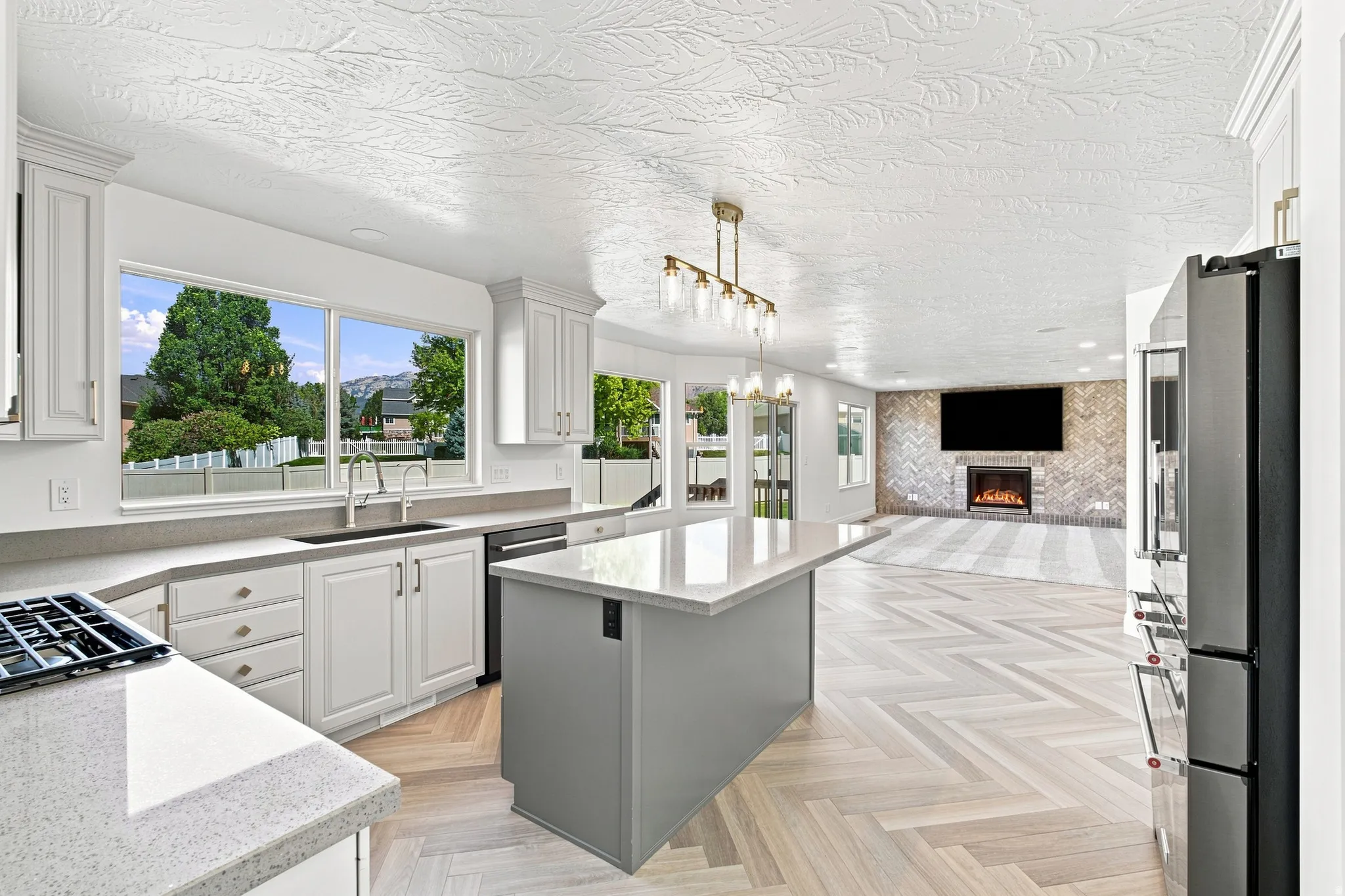Kitchen featuring white cabinetry, light-toned countertops, a center island, and wood-finish flooring in a herringbone pattern