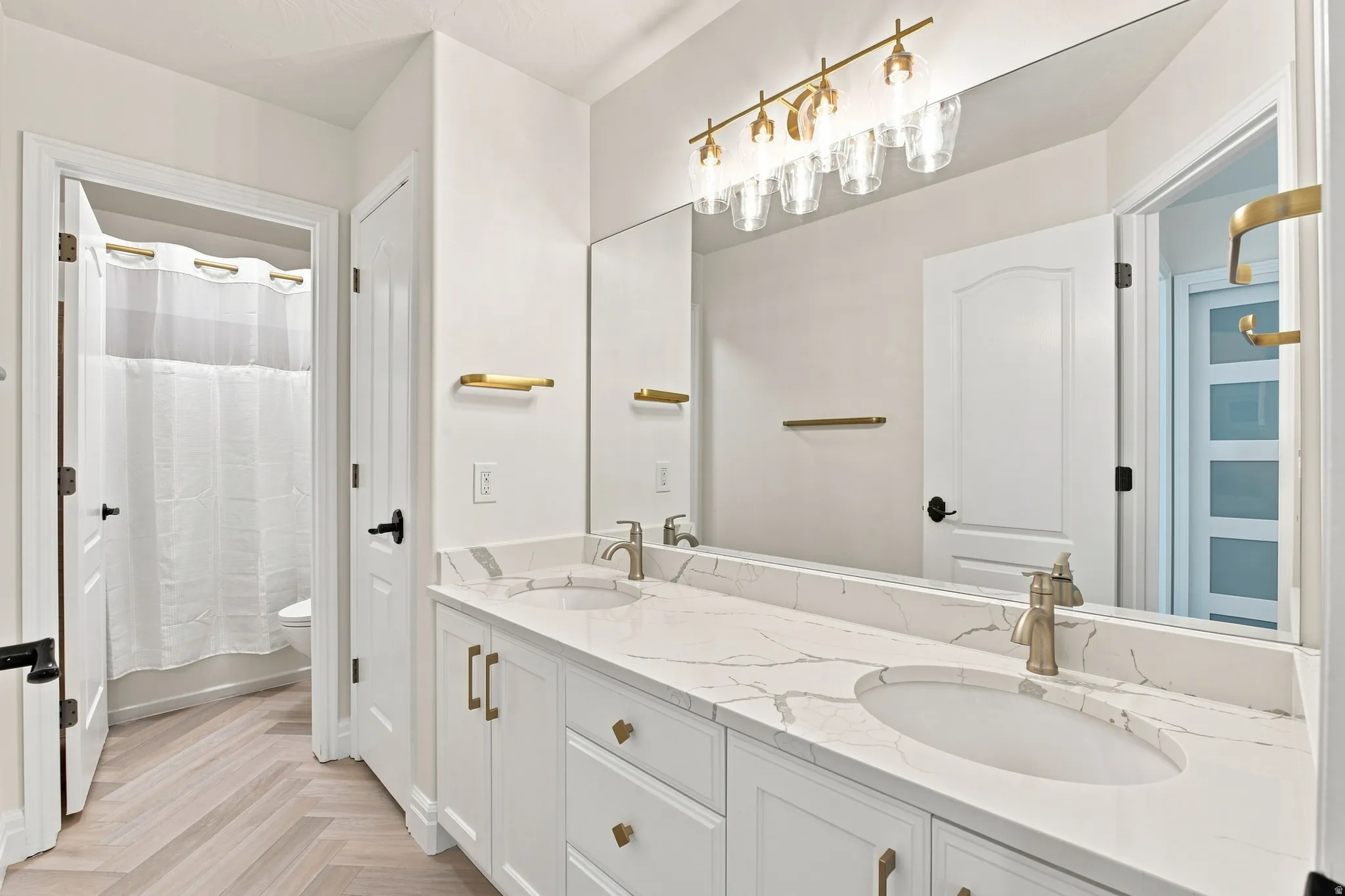 Double vanity with undermount sinks, stone-finish countertop, and brushed brass hardware