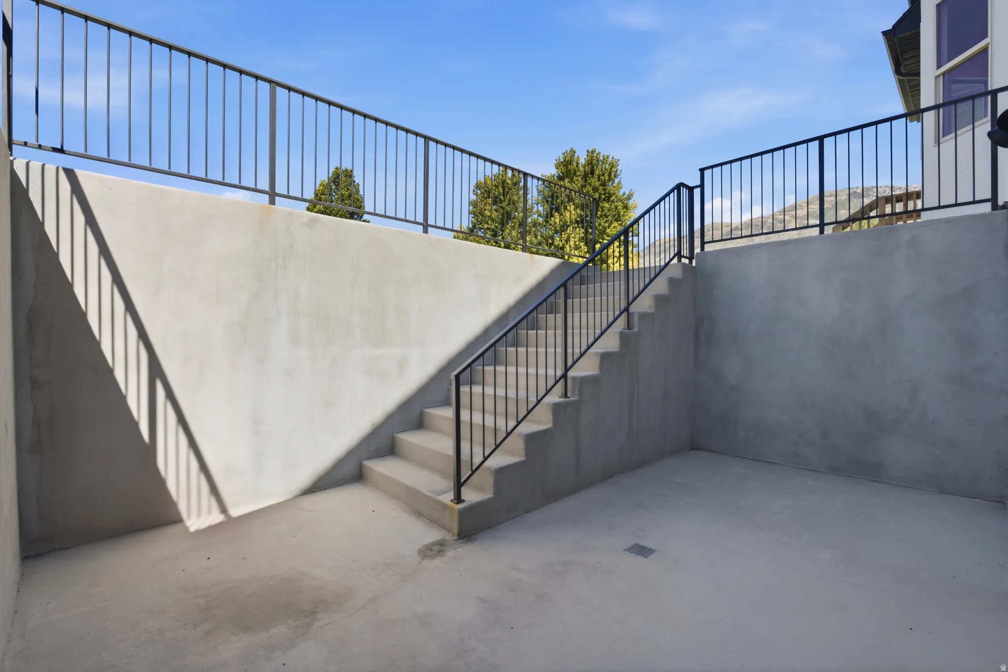 Concrete patio with concrete stairs and black metal railings