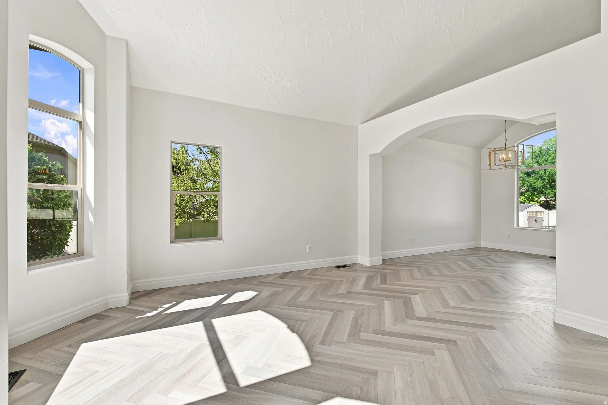 Archways and vaulted ceilings complement the herringbone wood-finish flooring