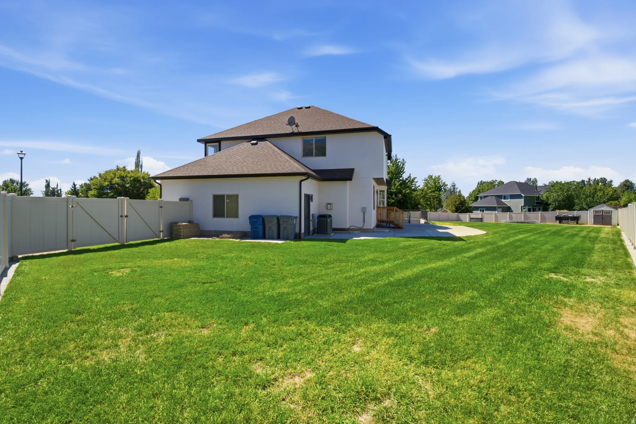 Expansive backyard featuring a manicured lawn, durable vinyl fencing, and a concrete patio