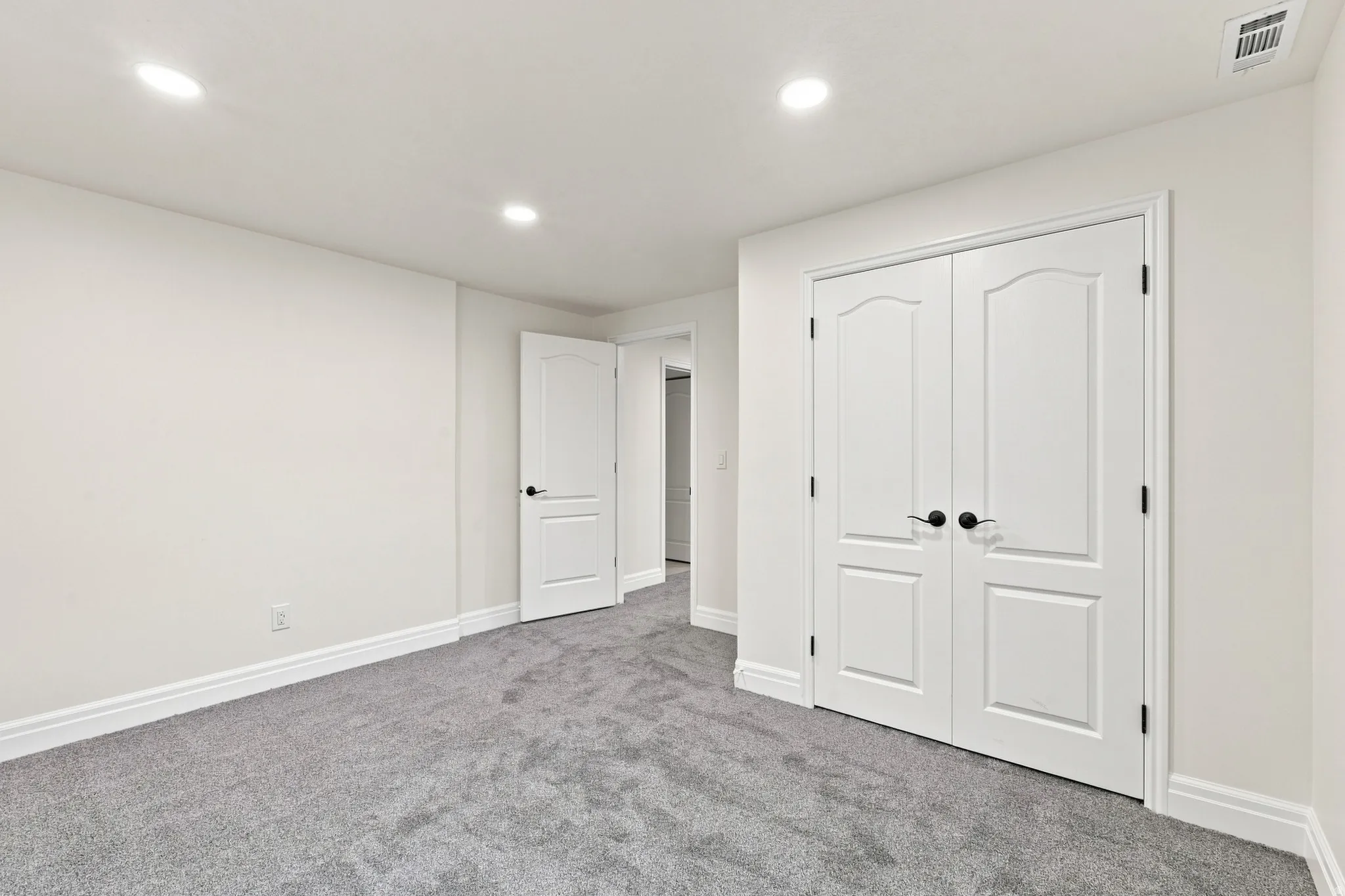Recessed lighting, plush carpeting, white interior doors, and matte black door hardware