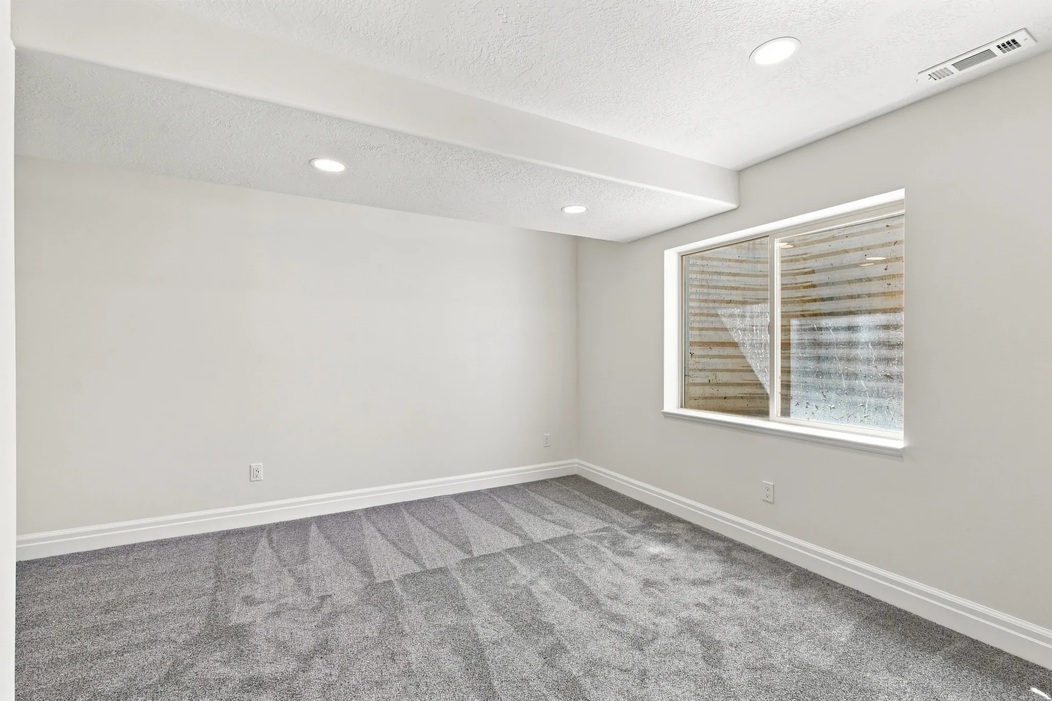 Recessed lighting illuminates the space, featuring light gray walls and patterned carpeting