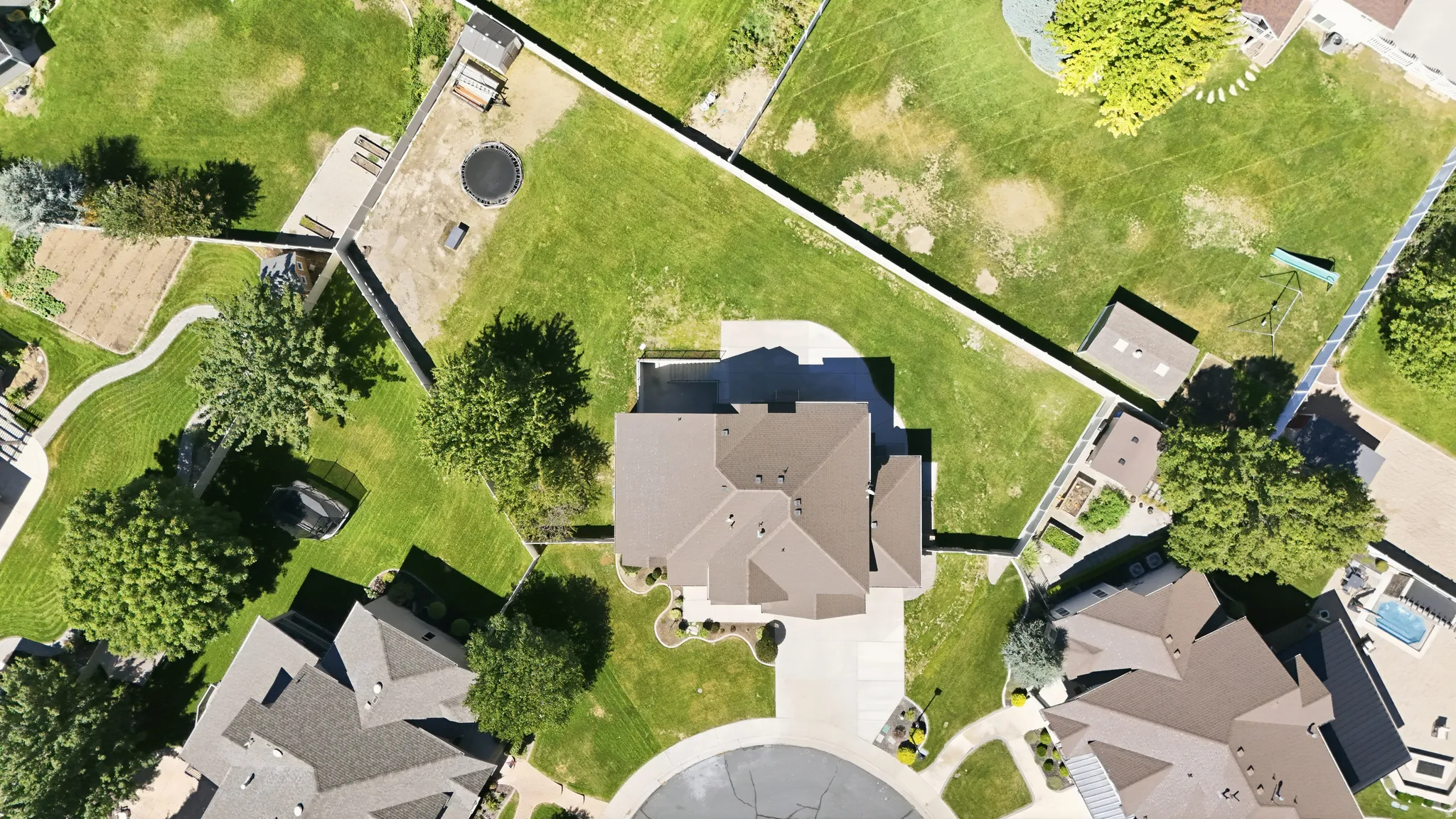 Expansive property featuring a central residence with a multi-pitched roof, paved driveway, and mature landscaping