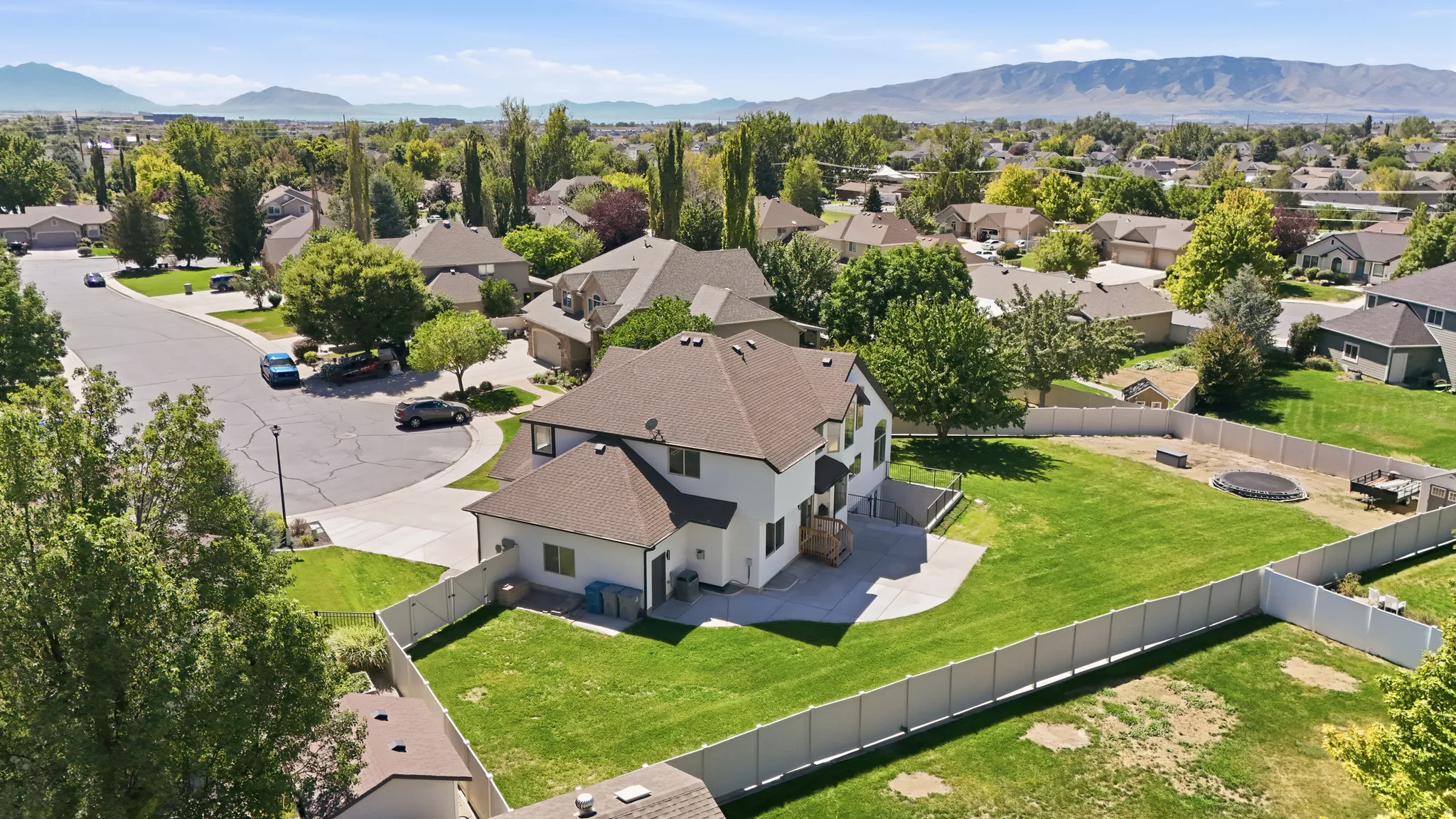 Expansive backyard with a manicured lawn, complete vinyl fencing, and a concrete patio