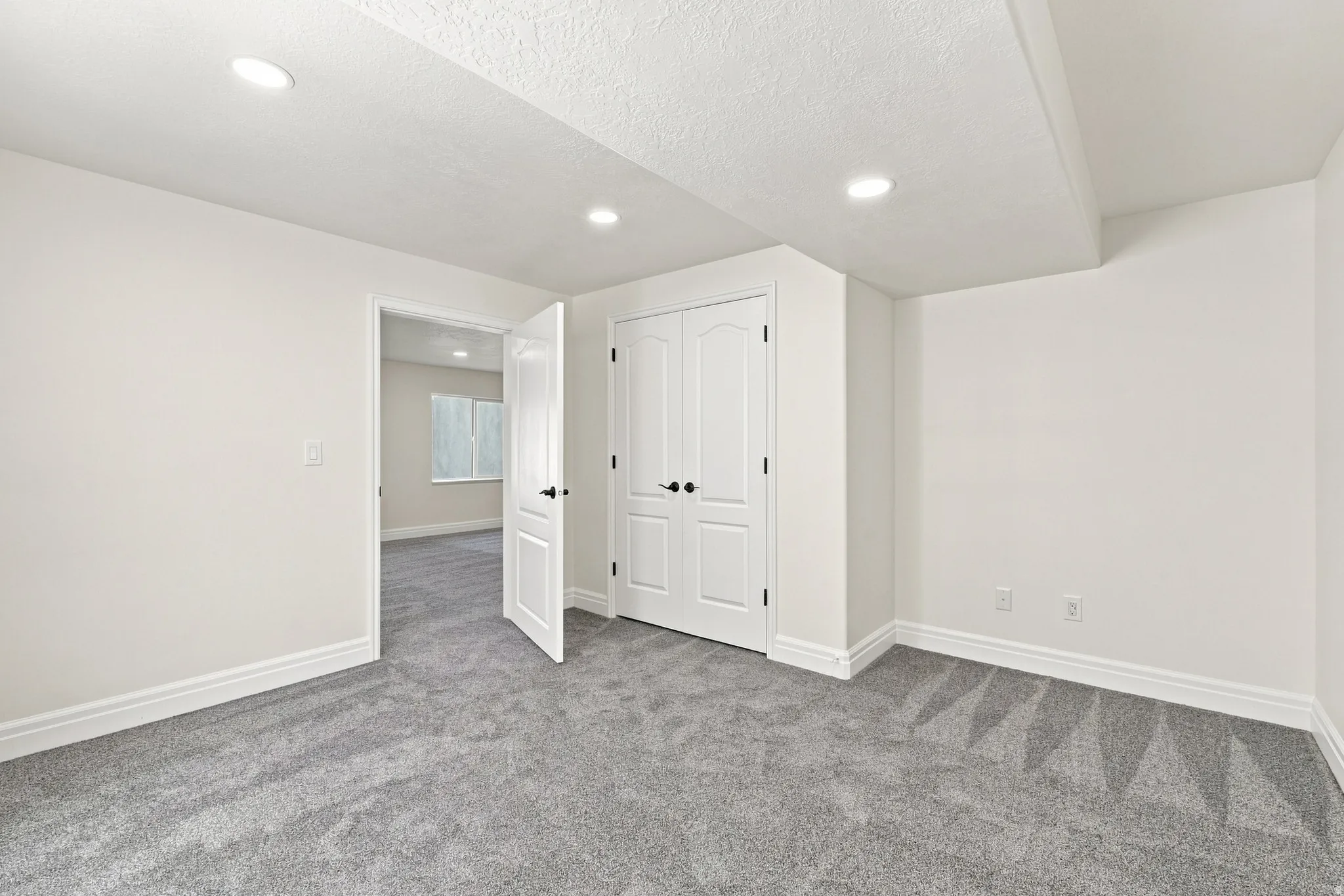 Recessed lighting, painted white walls, white trim, grey carpeting, and white paneled doors