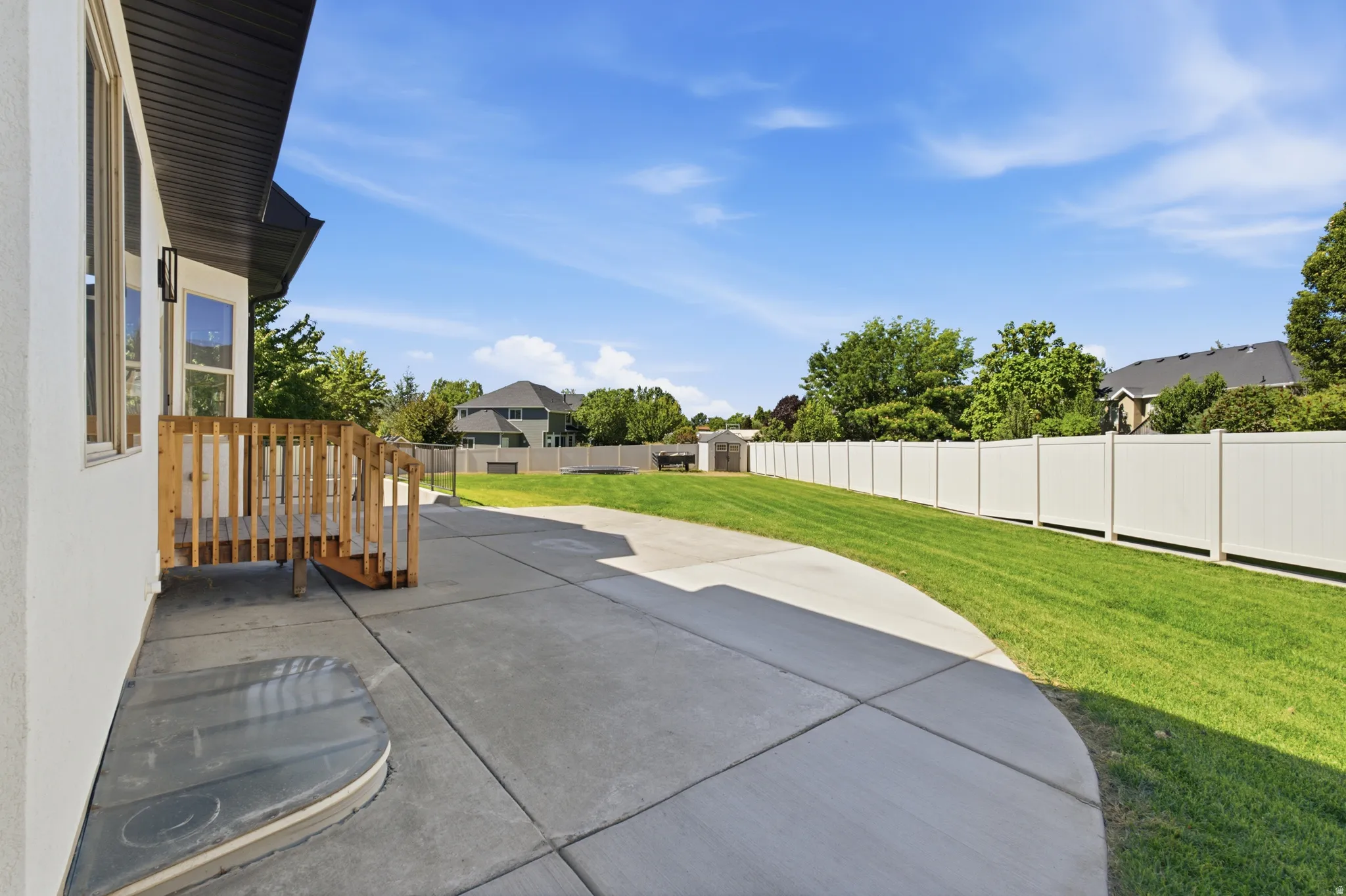 Expansive concrete patio with a wooden deck and stair access