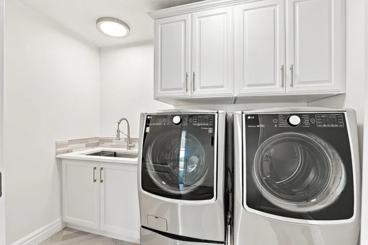 White shaker-style cabinetry, a built-in utility sink, and a tile backsplash