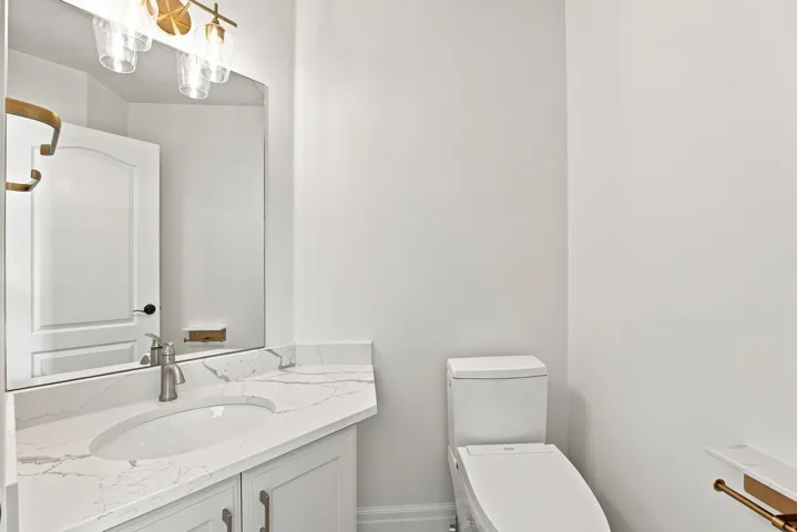 Vanity with a quartz countertop, an undermount sink, a brushed nickel faucet, and a wall-mounted mirror