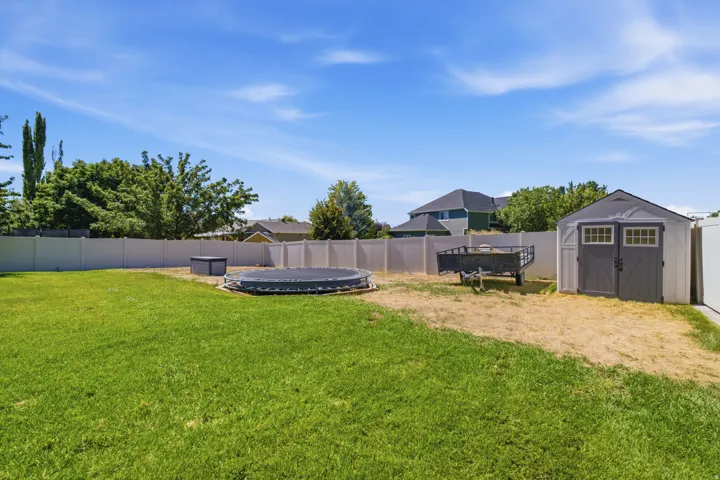 Expansive grassy yard with a privacy fence and a storage shed