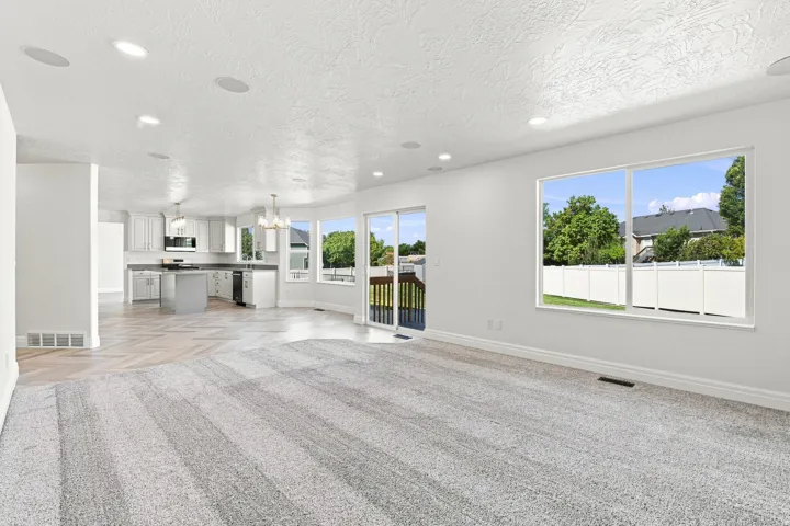 Recessed lighting, wood-finish flooring, white cabinetry, integrated kitchen appliances, and sliding glass door access to an outdoor deck