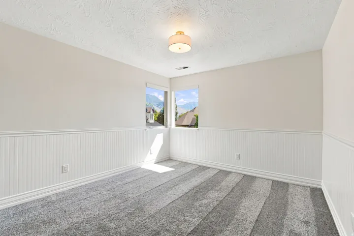 White wainscoting with decorative trim, neutral wall paint, and gray carpet flooring