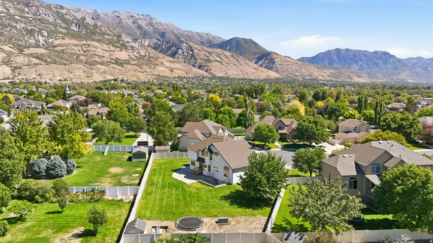 Expansive property featuring a multi-story residence, a large green lawn, and a white perimeter fence