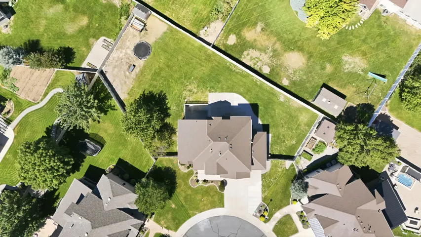 Expansive property featuring a central residence with a multi-pitched roof, paved driveway, and mature landscaping