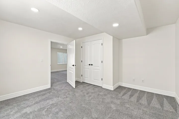 Recessed lighting, painted white walls, white trim, grey carpeting, and white paneled doors