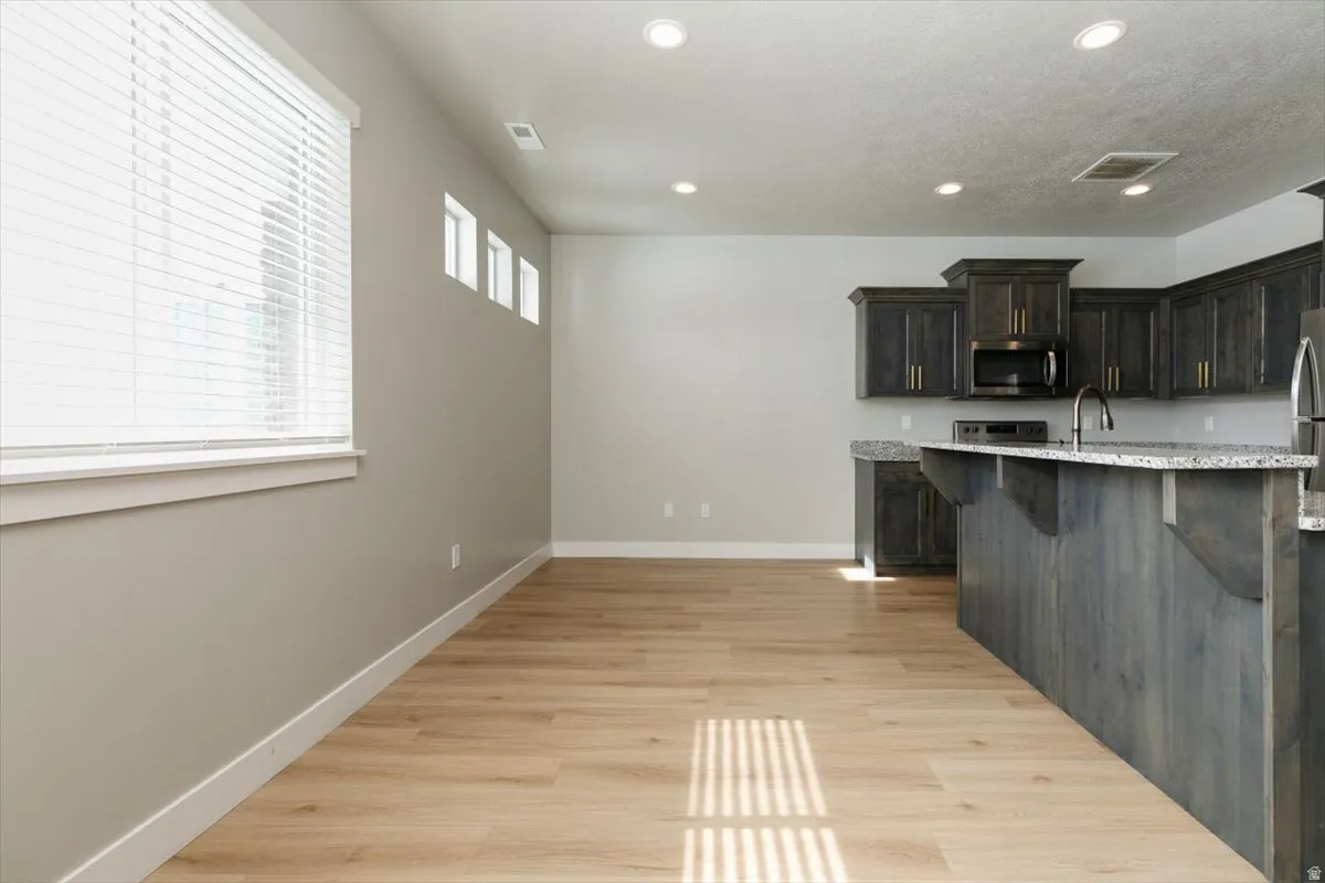 Open-concept living space with wood-finish flooring, recessed lighting, and a kitchen island with stone countertops