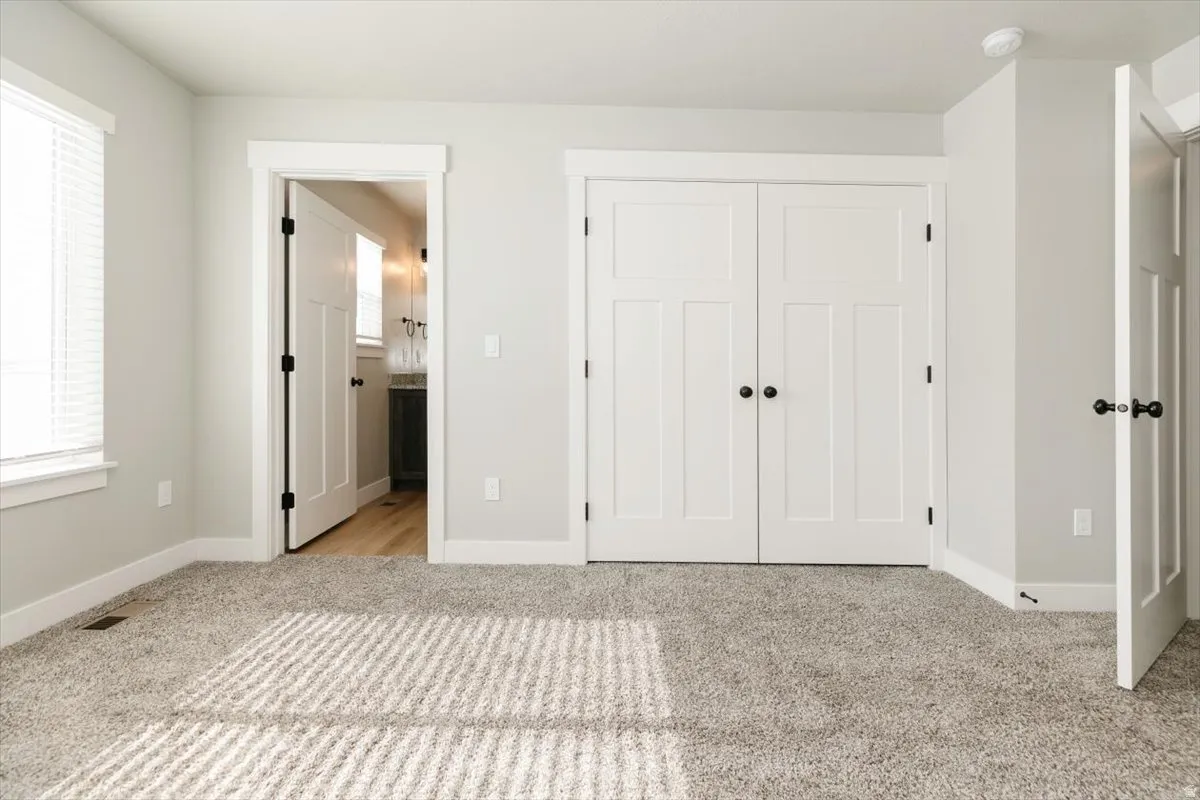 Neutral wall tones, panel-style interior doors, carpeting, and a window with blinds
