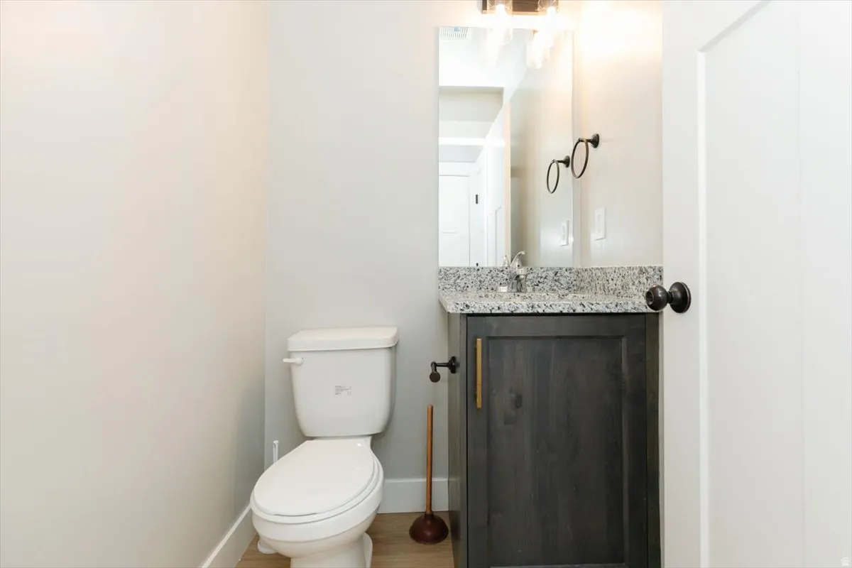 Vanity with a speckled countertop, dark wood-finish cabinetry, and a chrome faucet