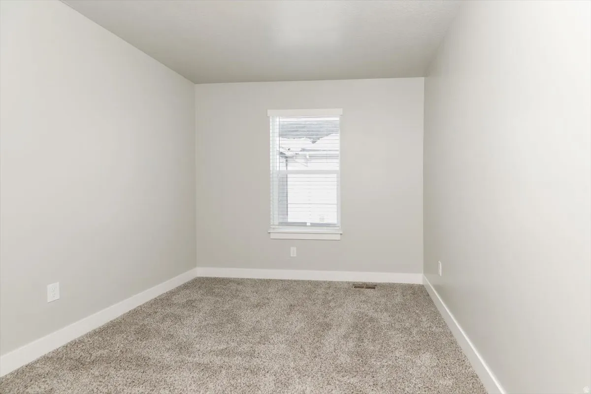 Textured carpeting, neutral wall color, and a window with blinds