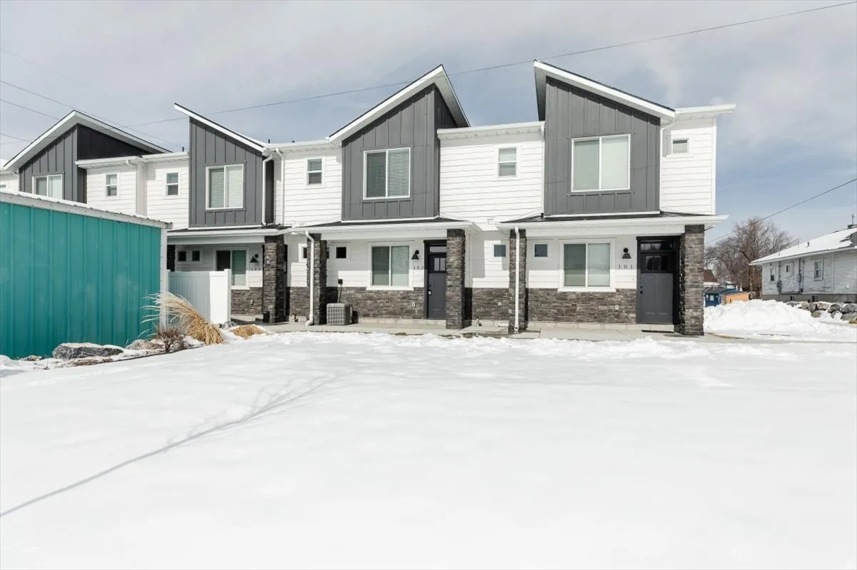Modern townhome exterior featuring an angular roofline, board and batten siding, horizontal siding, stone veneer accents, and dark-framed windows