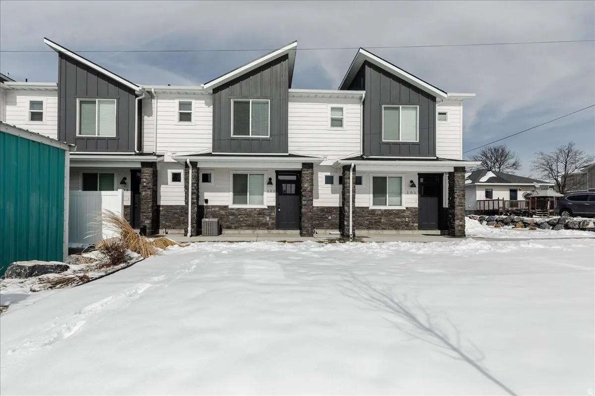 Modern exterior design featuring contrasting dark and light siding, prominent rooflines, and stone accent pillars