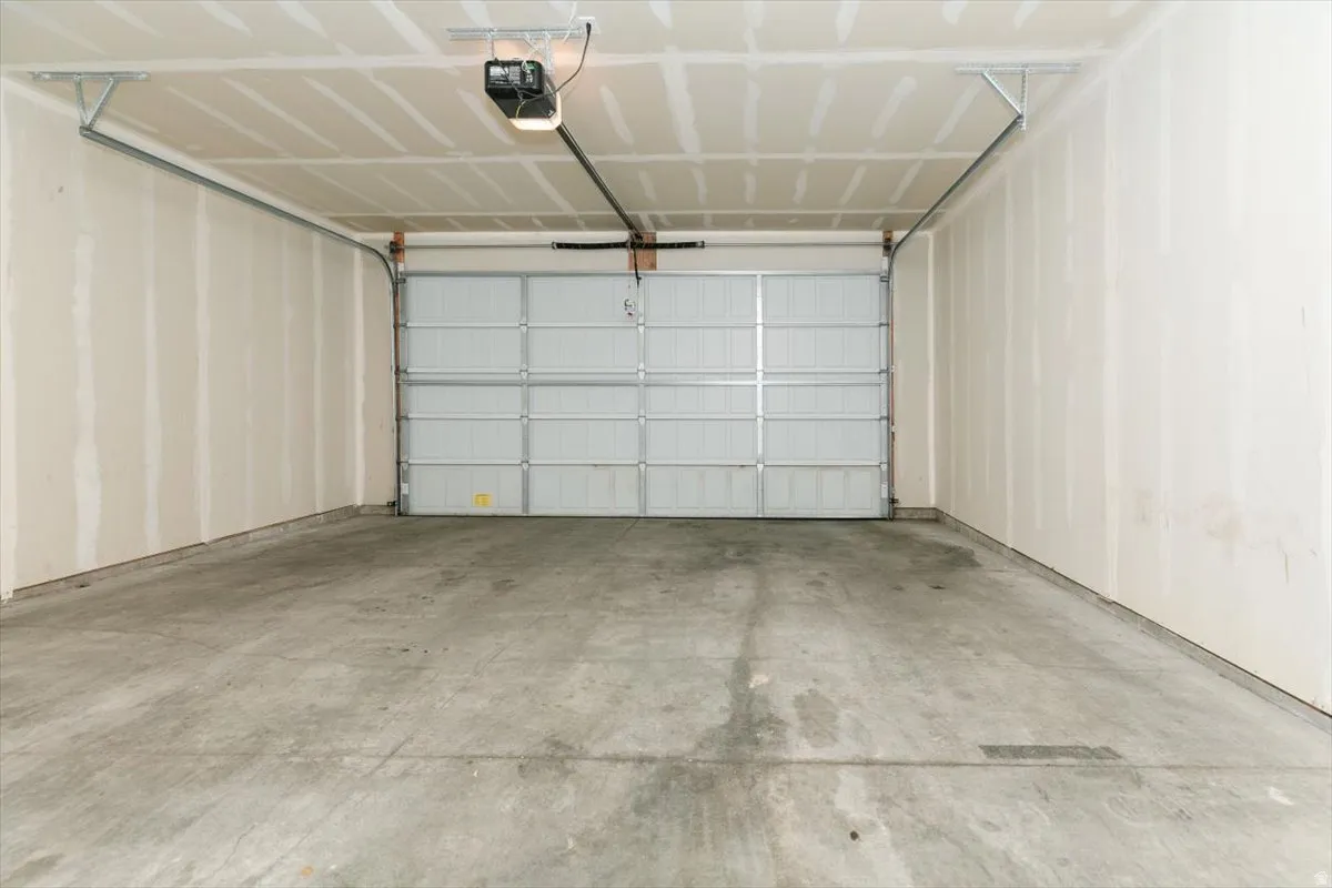 Attached garage with a concrete floor, an automatic garage door opener, and finished drywall walls and ceiling