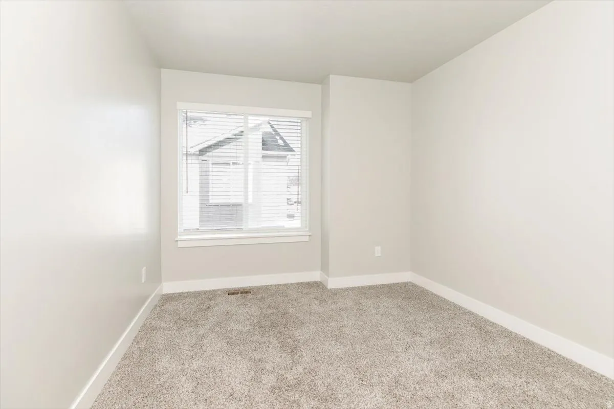 Carpeted room featuring a window with blinds, light-toned walls, and white trim