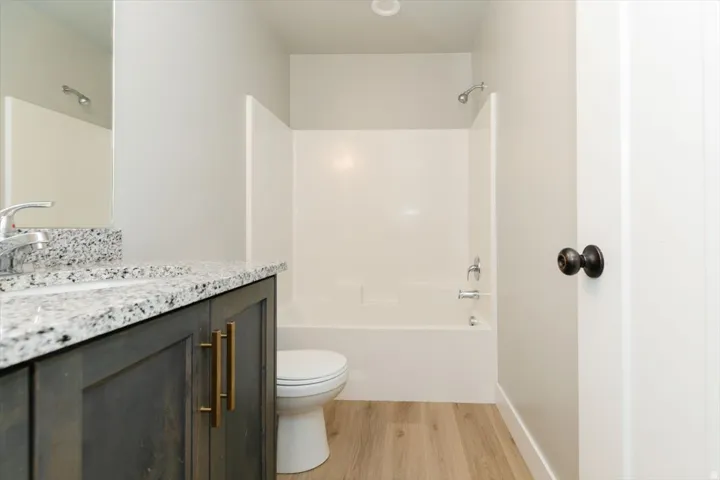 Wood-finish flooring with a white tub and shower combination