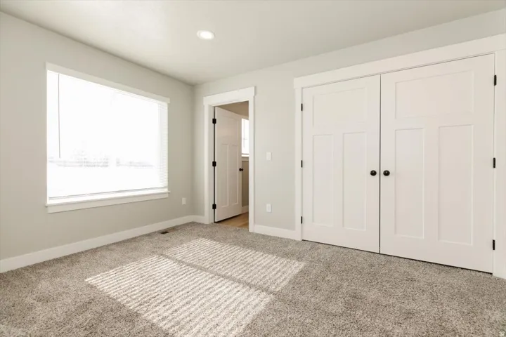 Carpeted room featuring a window with blinds, recessed lighting, and a closet with white paneled doors