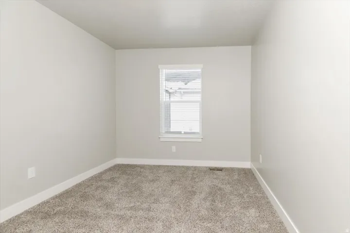 Textured carpeting, neutral wall color, and a window with blinds