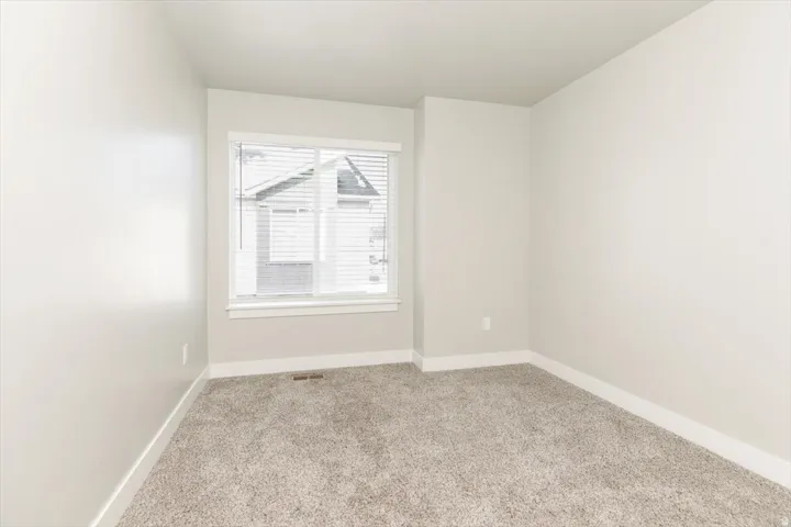 Carpeted room featuring a window with blinds, light-toned walls, and white trim
