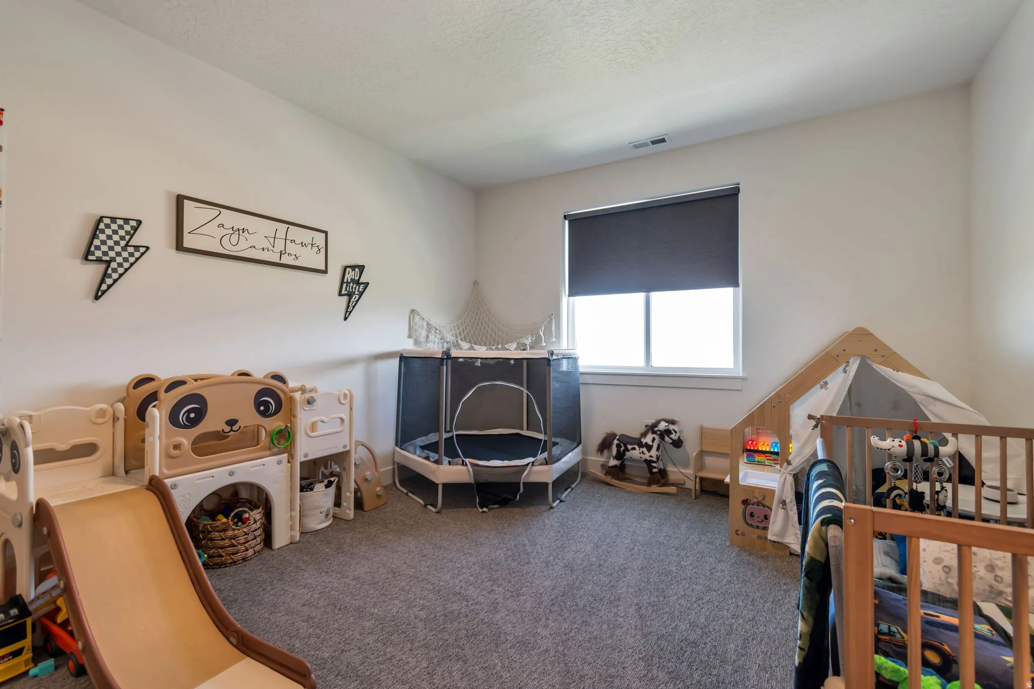 Carpeted room with a single window featuring a roller shade