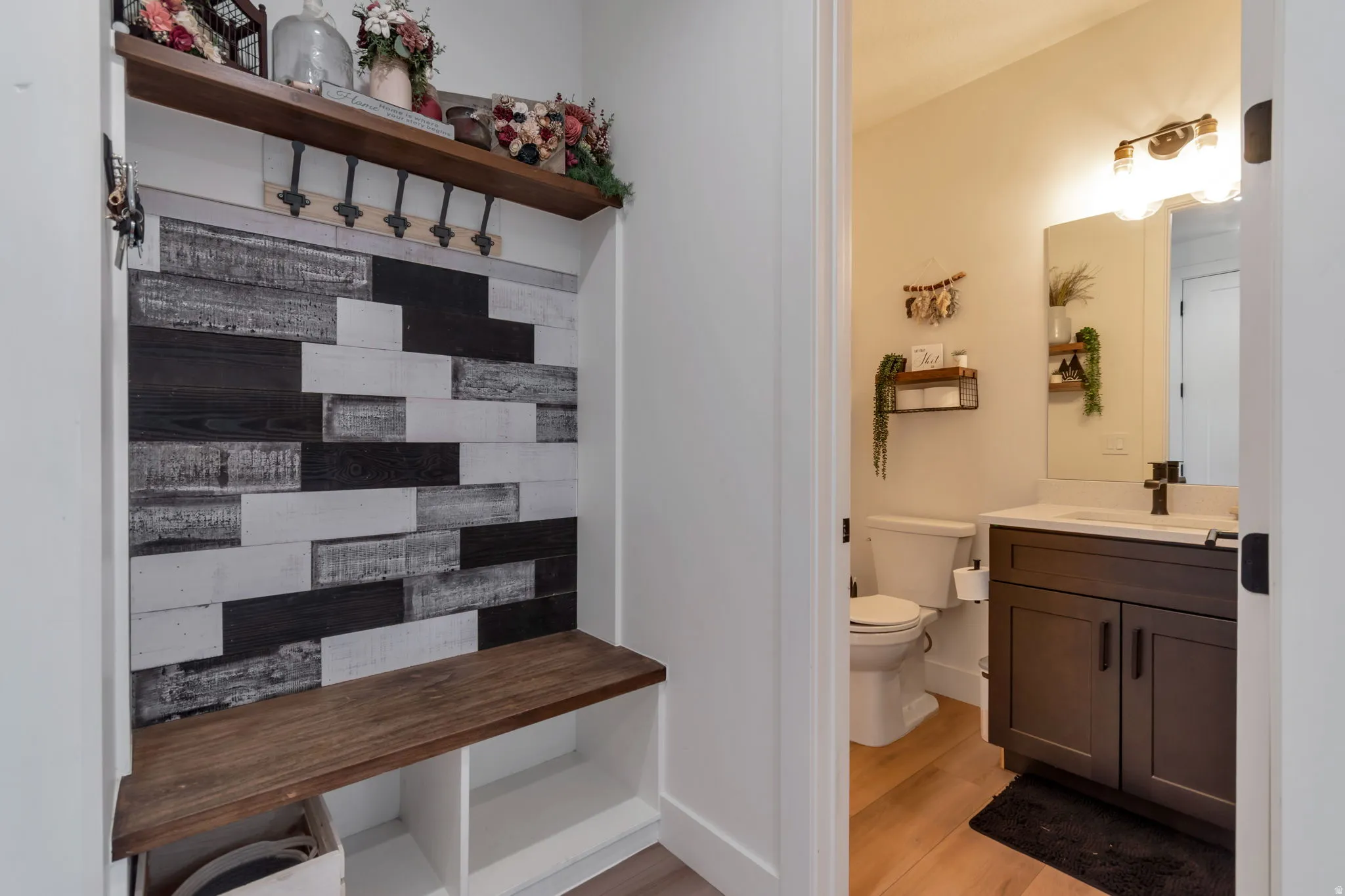 Built-in hall tree with a wood-finish bench and shelf, textured accent wall, and integrated coat hooks