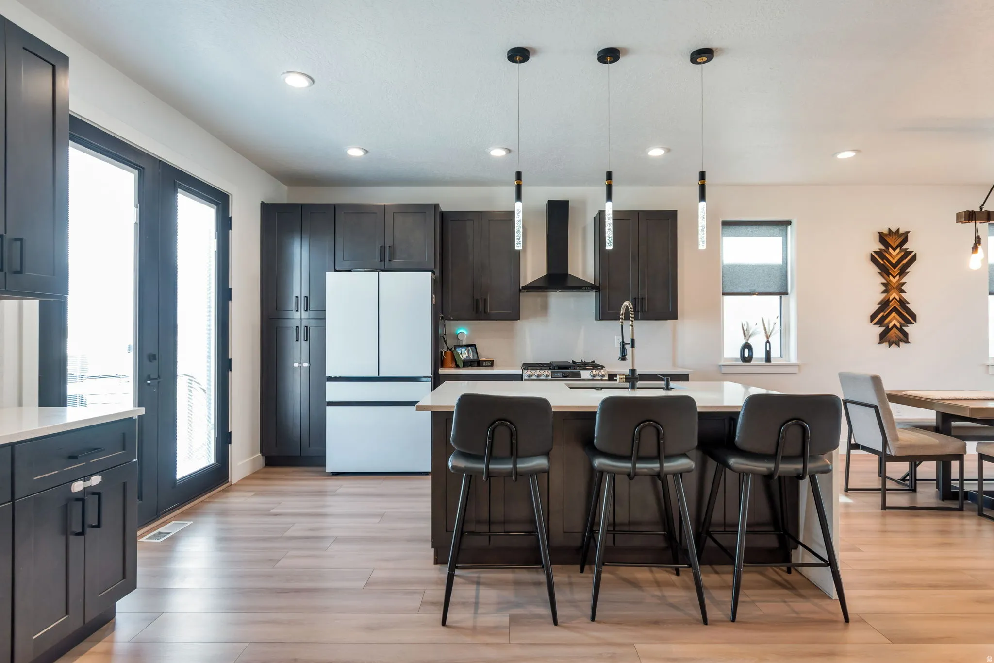 Kitchen featuring wood-finish flooring, dark cabinetry, and a center island with pendant lighting