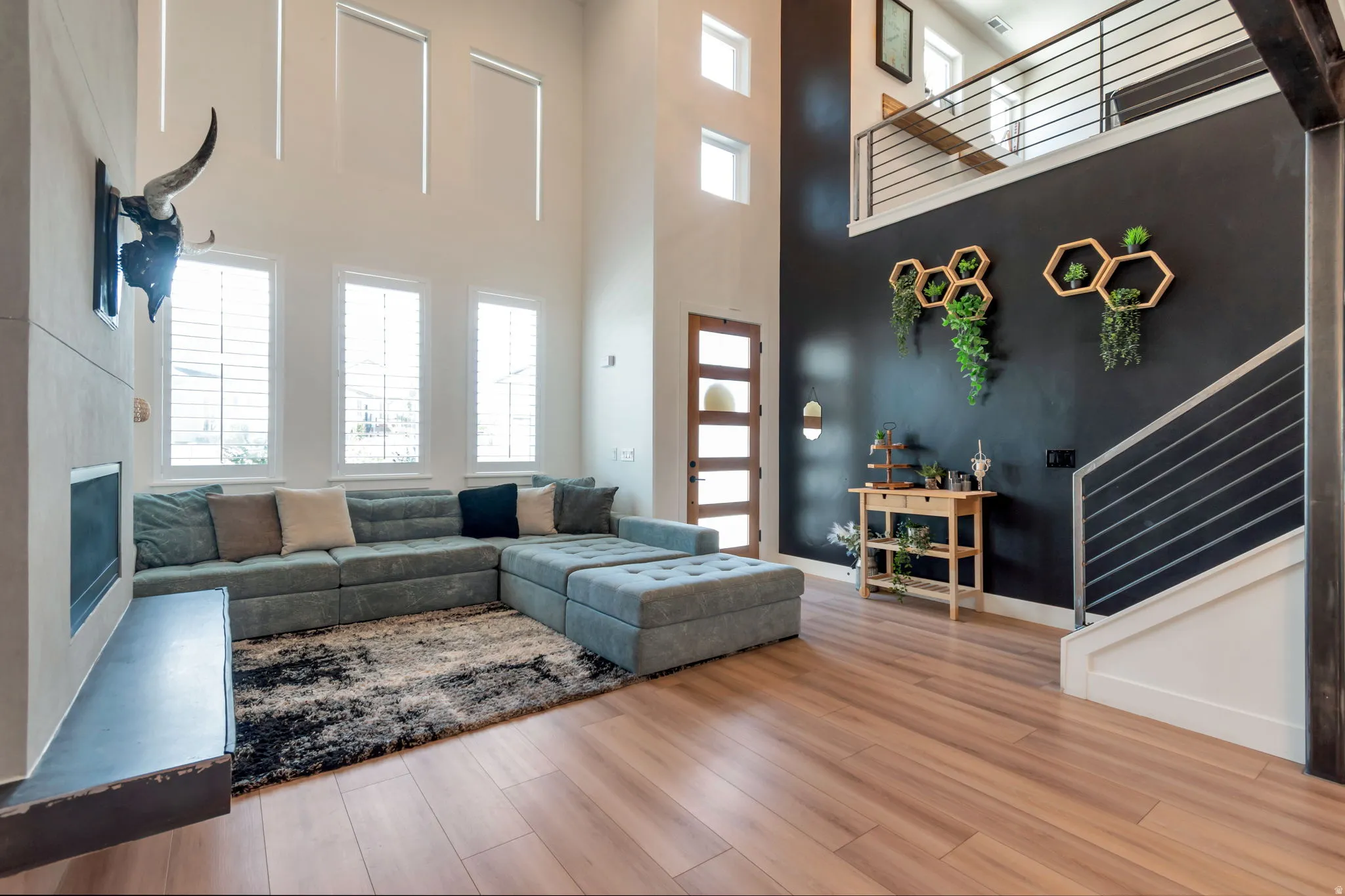 Two-story living area featuring a fireplace with hearth, wood-finish flooring, and multiple windows