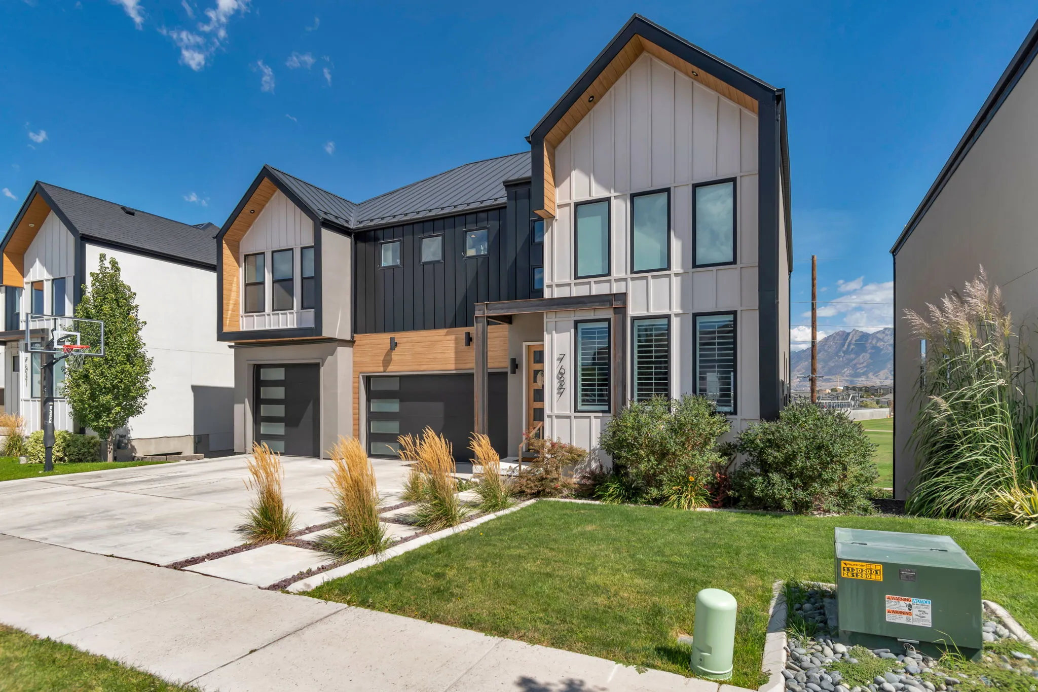 Modern exterior featuring vertical siding, a black metal roof, and a concrete driveway with integrated landscaping