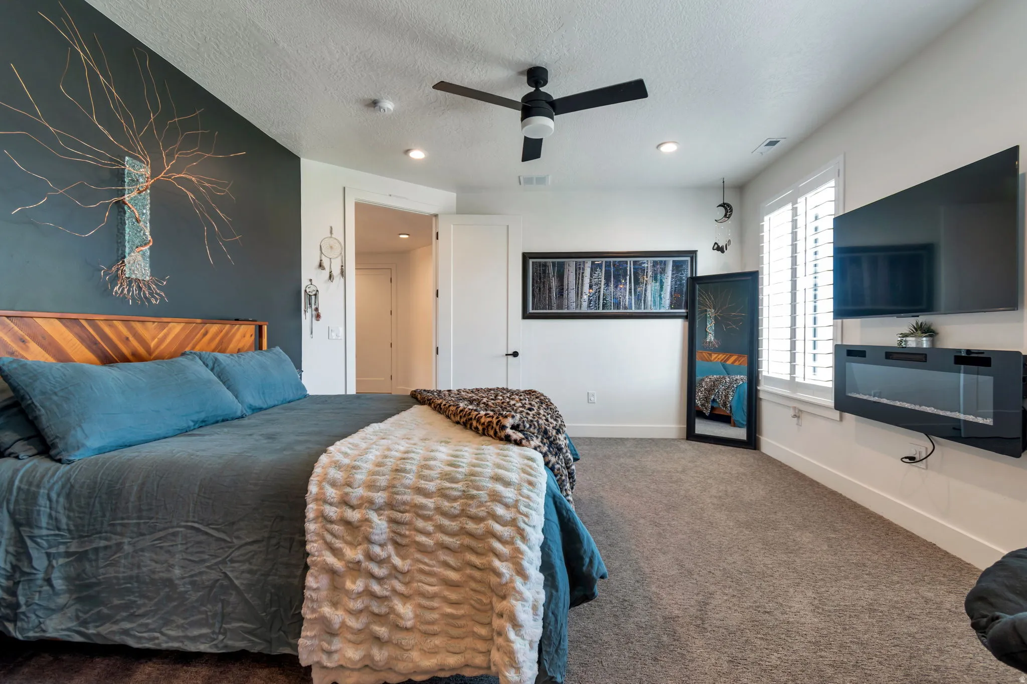 Wood-finish flooring, accent wall, ceiling fan, recessed lighting, and wall-mounted electric fireplace