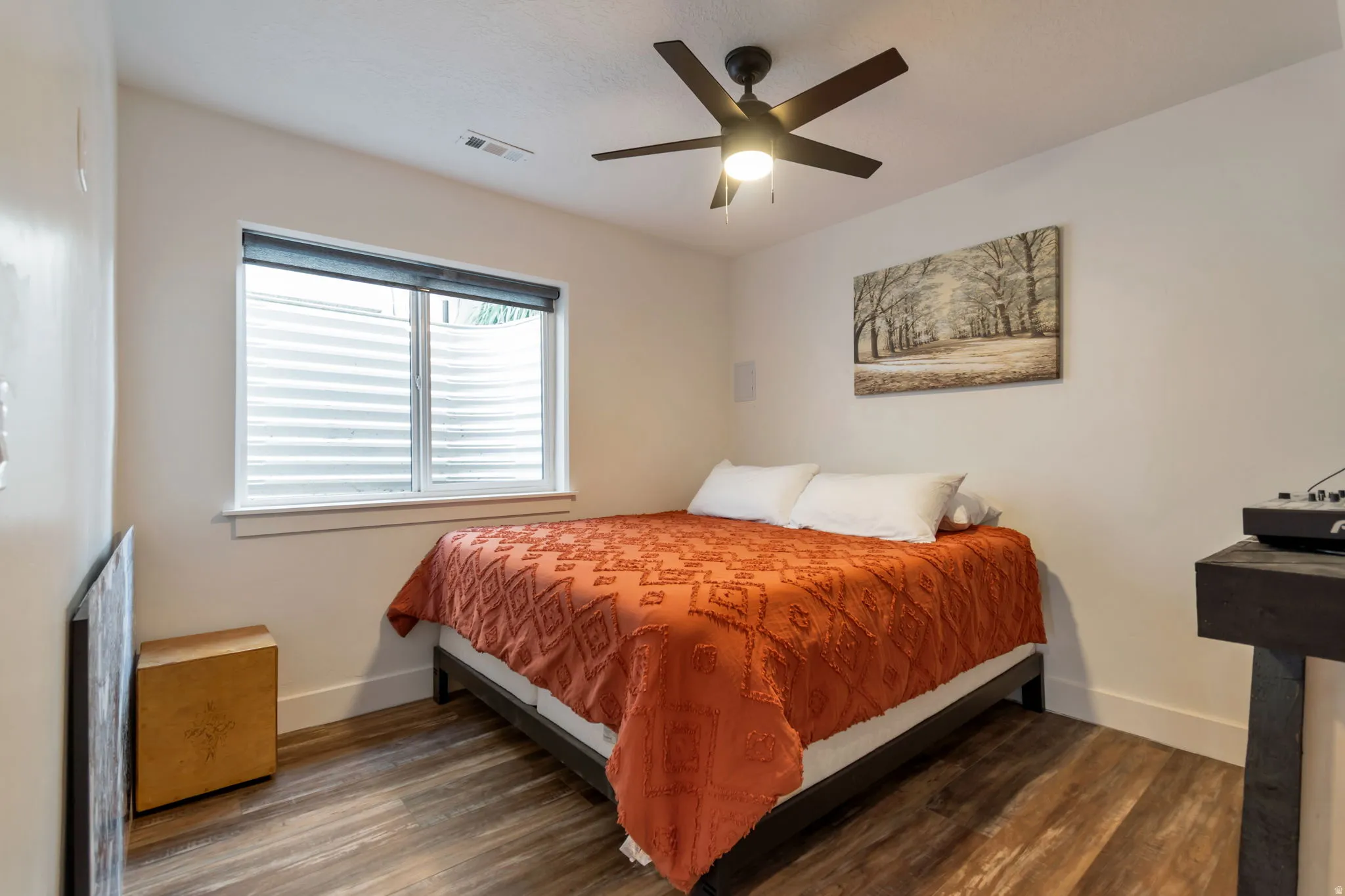 Room featuring wood-finish flooring, a ceiling fan with integrated lighting, and a window with blinds