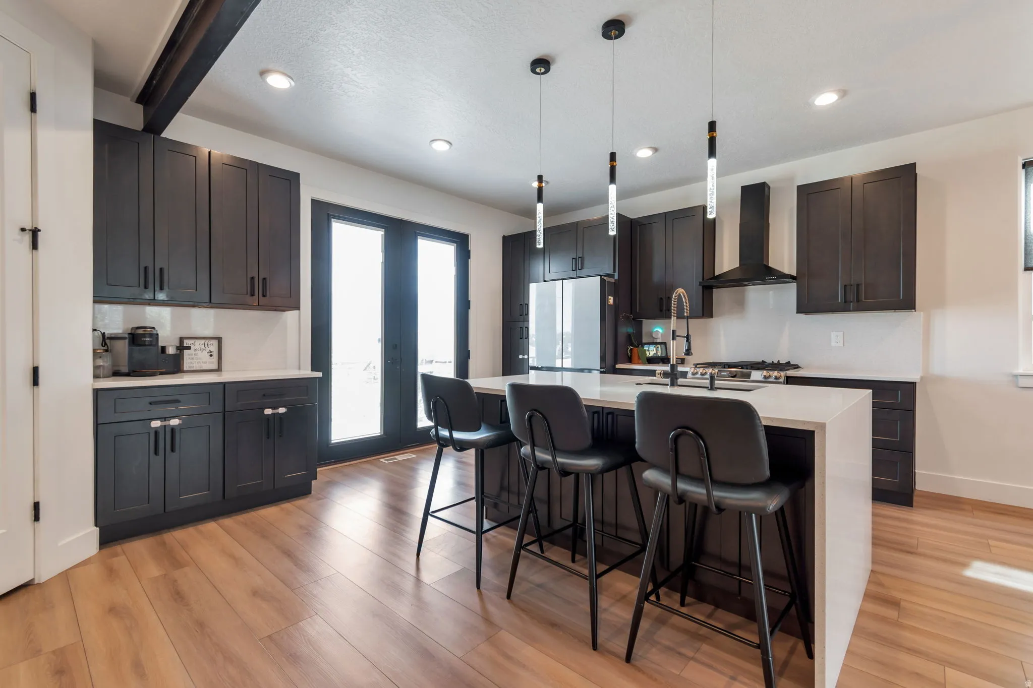Kitchen with dark cabinetry, light countertops, wood-finish flooring, recessed lighting, and a kitchen island with pendant lights