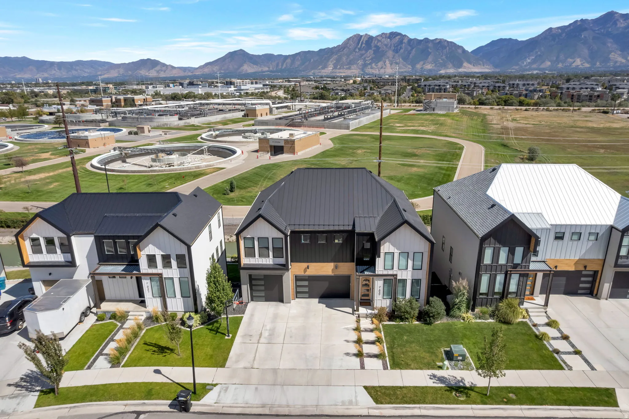 Modern residential architecture featuring black metal roofs, white vertical siding, and integrated garages